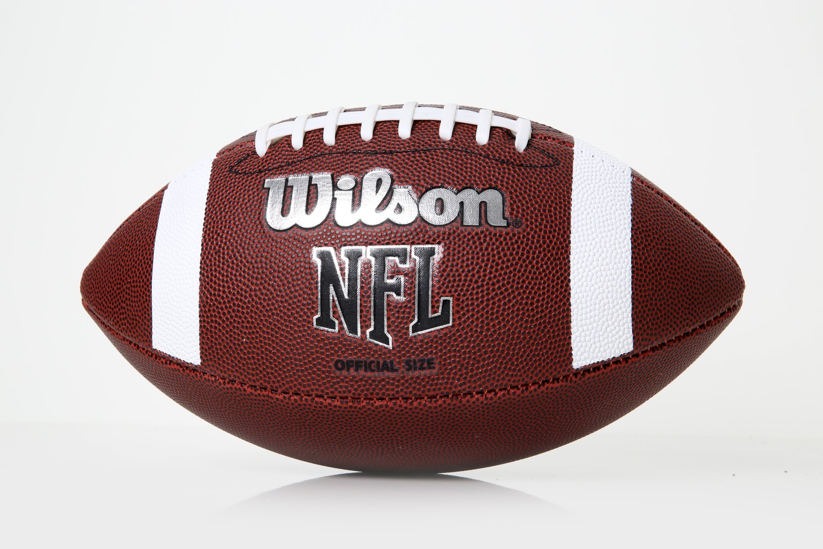 Closeup of a brown American football with white laces and stripes against a plain light background. Illustrative photo.