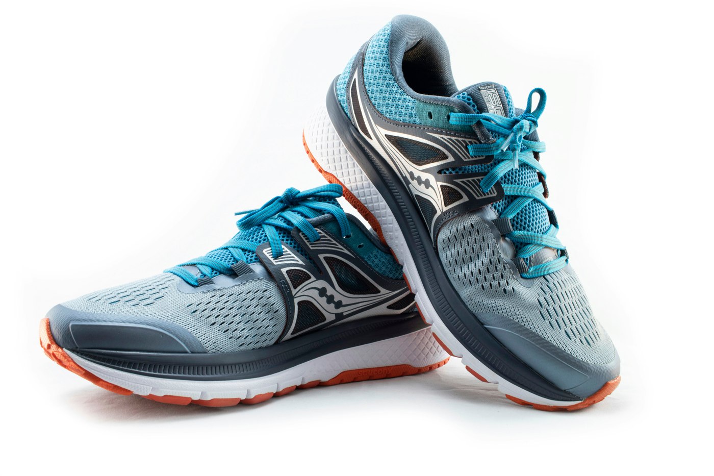 A pair of gray and turquoise running shoes with orange soles on a white background. Illustrative photo.